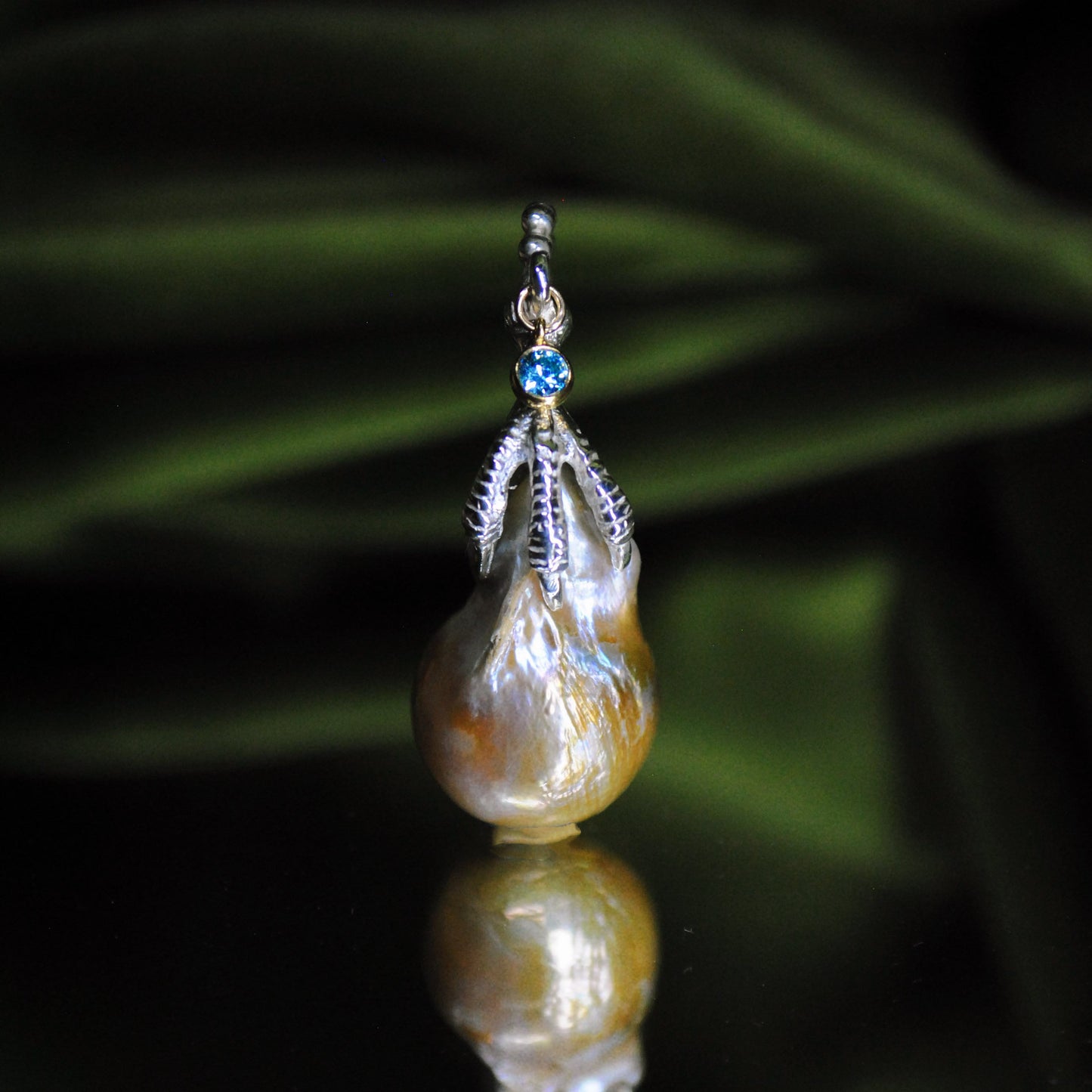 Pearl charm with a dark green leafy background