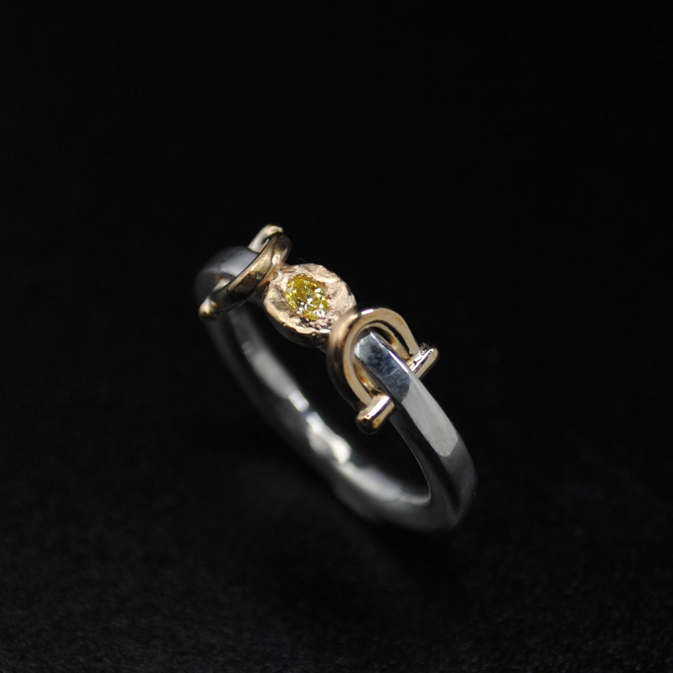 Gold and black ring with a diamond on a dark background