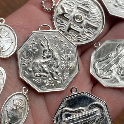 Collection of silver jewelry pendants on a hand